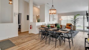 A spacious dining area with a wooden table and chairs, pendant lighting, and a view of the outdoors. - 4BR Family Getaway w/Pool (North Las Vegas)