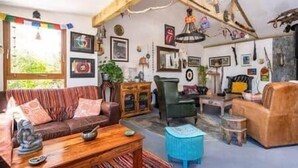 A cozy living room with a sofa, a wooden coffee table, and a green armchair. - The Hideaway - Shore House (Muff)