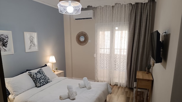 Ett välordnat sovrum med en säng, sänglampor, en spegel och en tv på väggen.