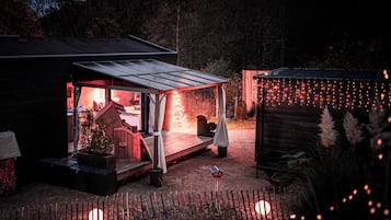 A cozy outdoor seating area with a wooden deck, a covered patio, and string lights.