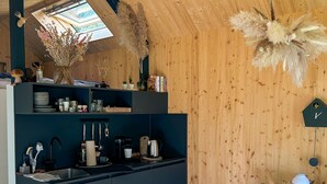 A modern kitchen with a skylight, wooden walls, and a dining area with a table and chairs.