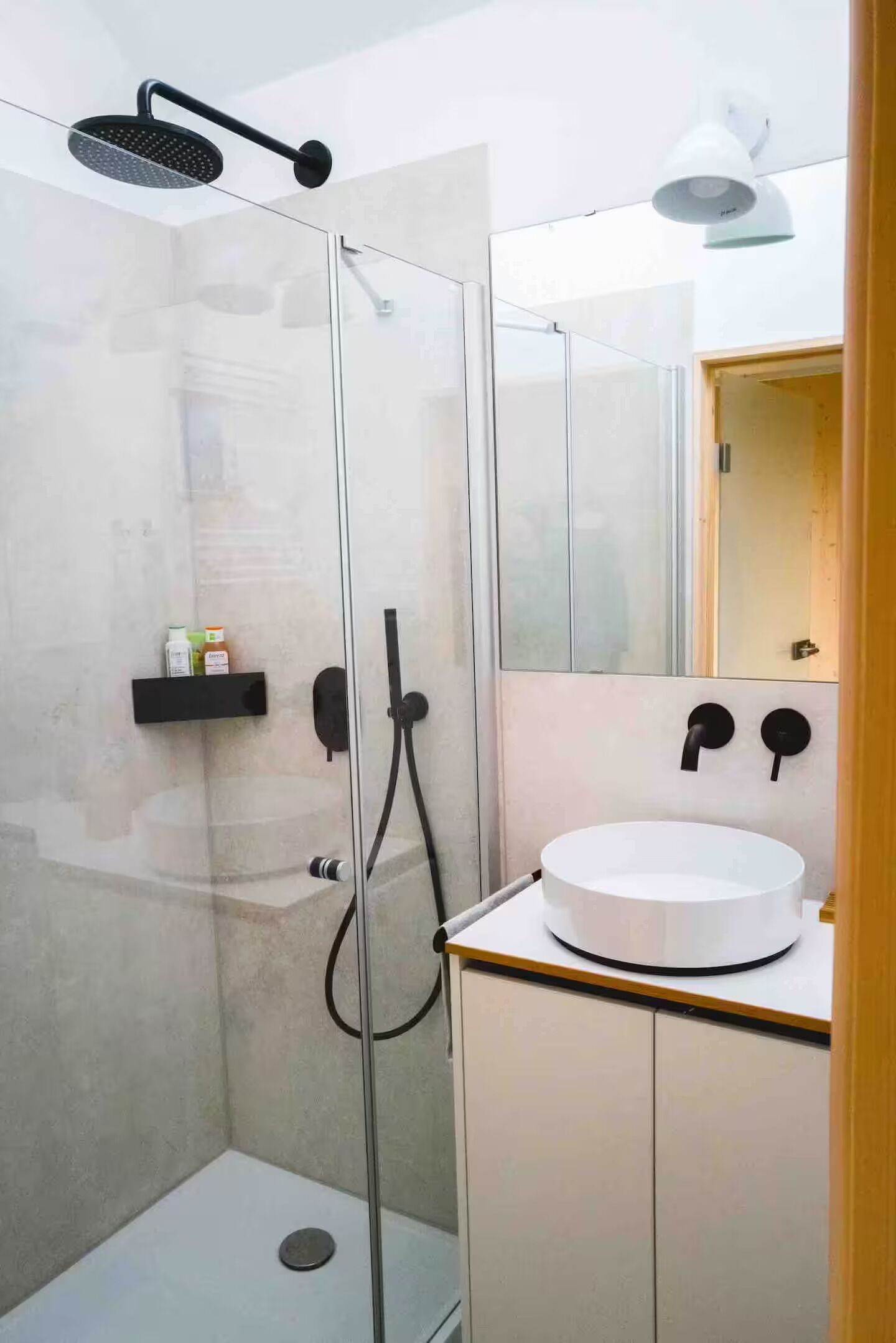 A modern bathroom with a glass-enclosed shower, a white sink, and a mirror above the sink.