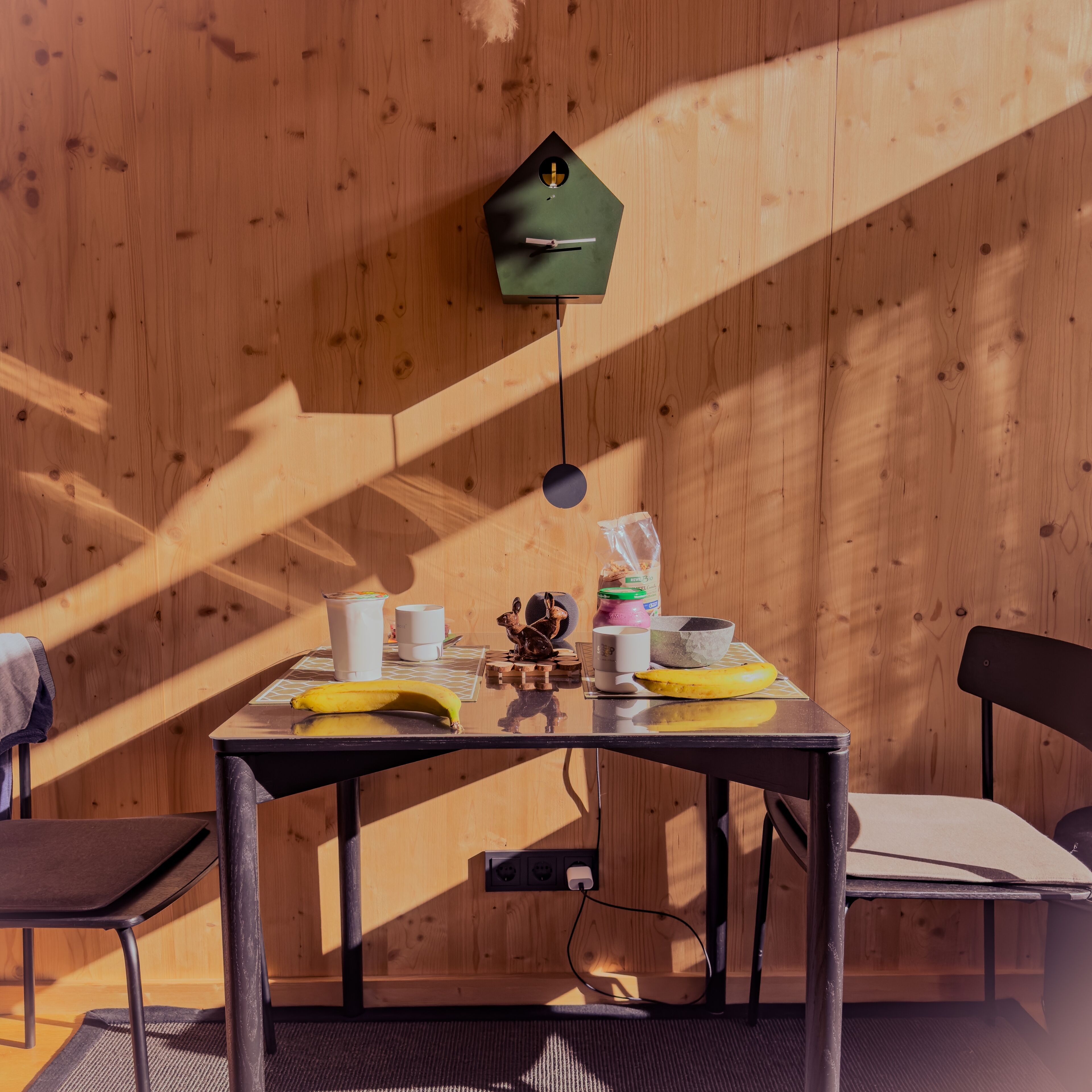 Un intérieur en bois avec une table mise pour le petit-déjeuner, comprenant une banane, une tasse et un bol.