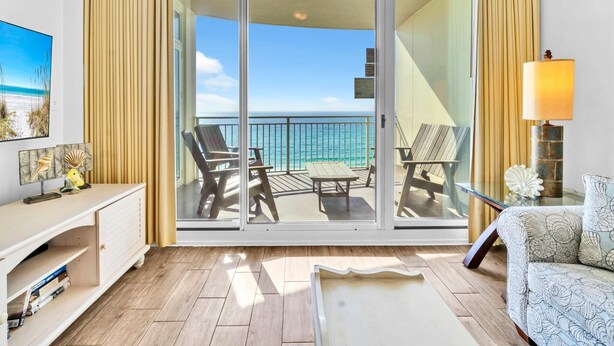 Un balcon avec deux chaises et une table, un canapé, un téléviseur et une lampe.