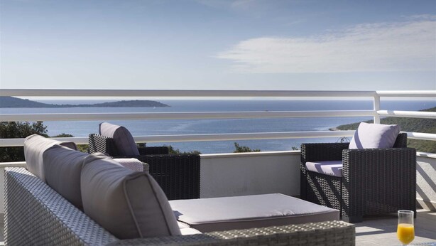A balcony with wicker furniture and a view of the sea. - Villa Whispering Bay by MyWaycation (Ljubljeva)