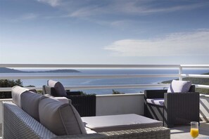 A balcony with wicker furniture and a view of the sea. - Villa Whispering Bay by MyWaycation (Ljubljeva)