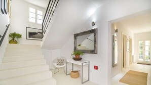 A modern interior with a staircase, a white console table with a mirror, and a potted plant. - Villa Whispering Bay by MyWaycation (Ljubljeva)