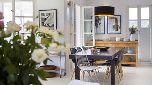 A modern dining area with a round table, chairs, and a hanging light fixture. - Villa Whispering Bay by MyWaycation (Ljubljeva)