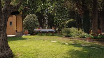 A courtyard with a table set for dining, surrounded by trees and potted plants.