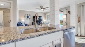 Een moderne keuken met granieten aanrechtbladen, roestvrijstalen apparatuur en een groot keukenblok met een spoelbak.