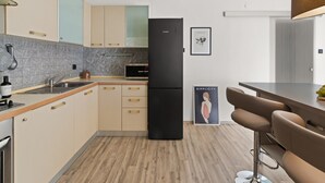 A modern kitchen with a black refrigerator, wooden cabinets, a tiled backsplash, and a bar area with stools. - Premium Apartment With Patio (Porec)