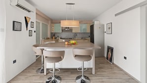 A modern kitchen with a central island, bar stools, and a hanging light fixture. - Premium Apartment With Patio (Porec)