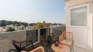 A balcony with wicker chairs and a table, overlooking a residential area with houses and trees. - Premium Apartment With Patio (Porec)