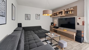 A modern living room with a sectional sofa, a flat-screen TV, a coffee table, and a wooden entertainment unit. - Premium Apartment With Patio (Porec)