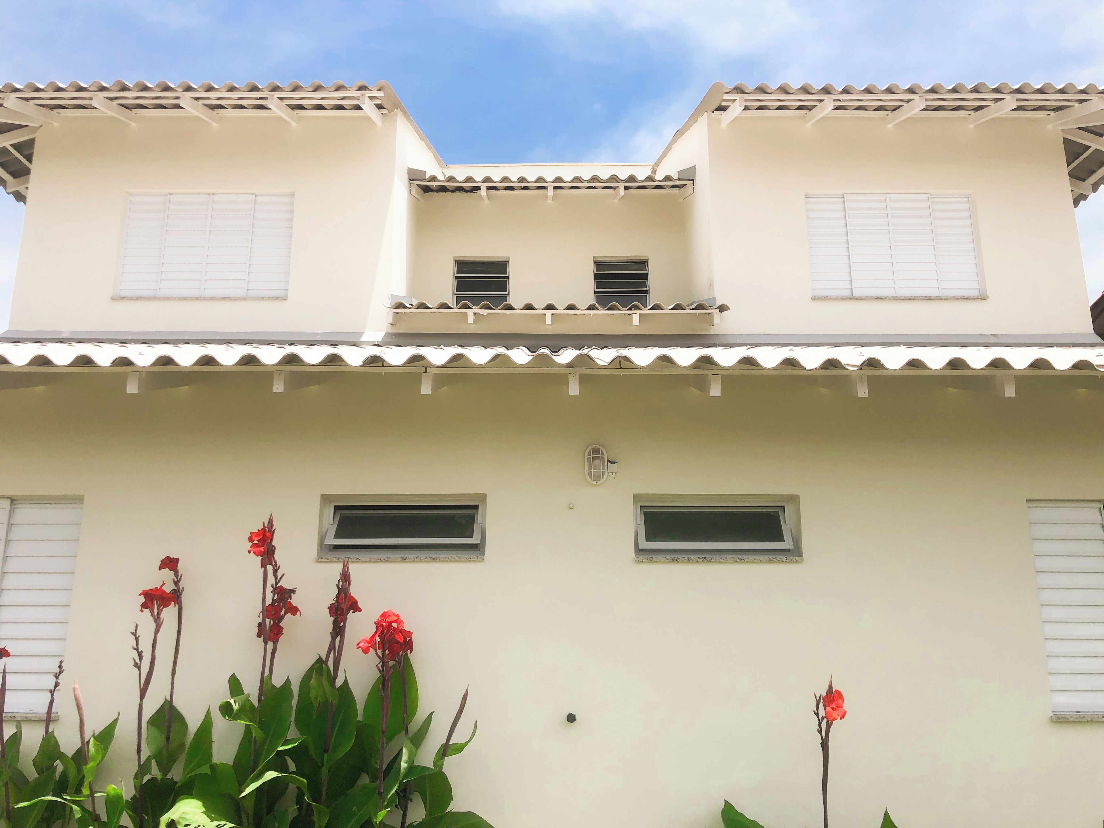 Un edificio de dos pisos con techo plano y detalles blancos. Tiene dos ventanas en el piso superior y dos en el piso inferior.