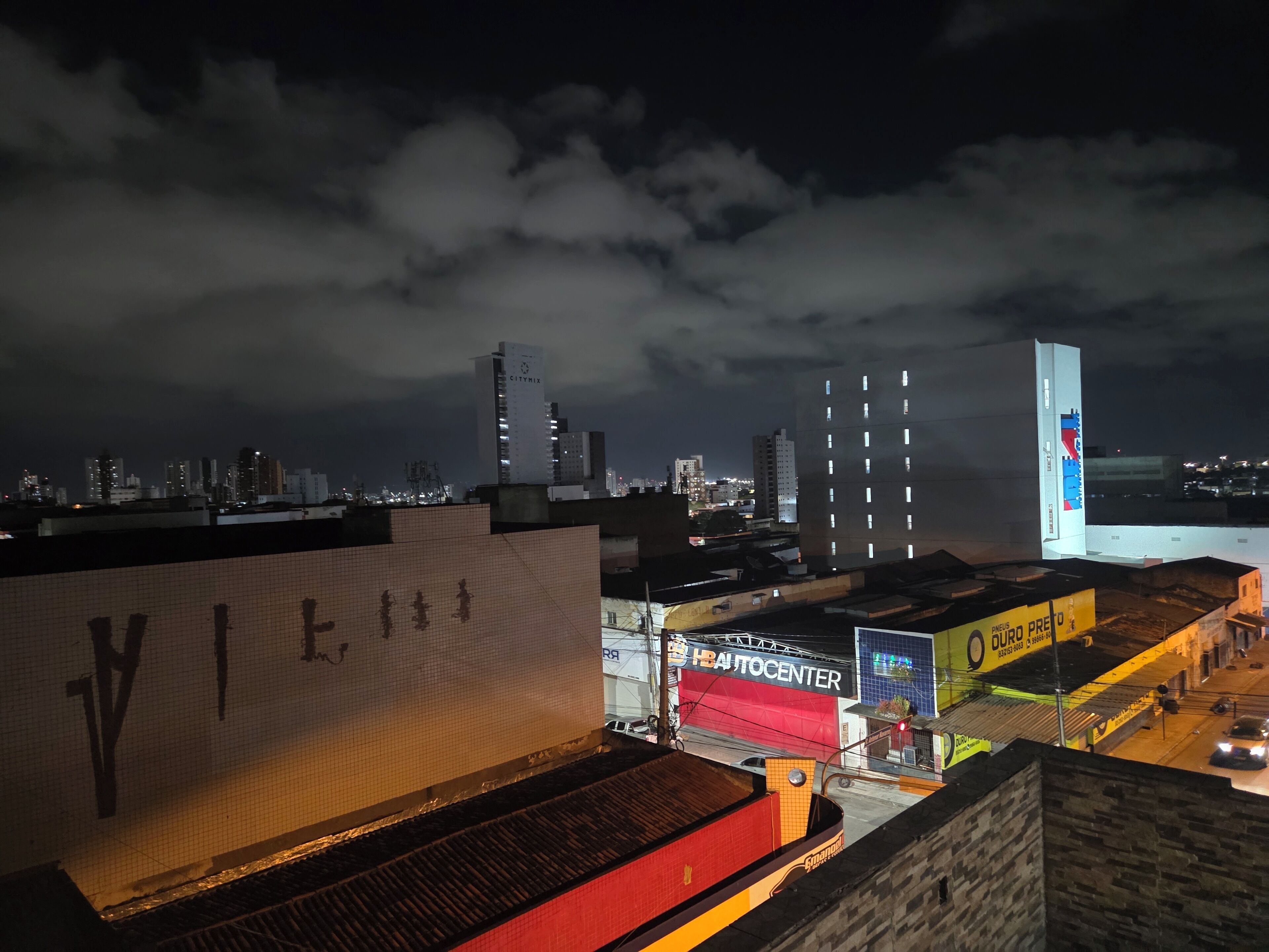 A cityscape at night with illuminated buildings and a prominent 'CityMix' sign.