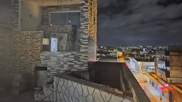 Un edificio moderno con una fachada geométrica distintiva y vistas a una ciudad de noche.