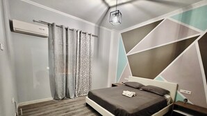 Une chambre moderne avec un lit, des rideaux, un climatiseur et un motif géométrique sur le mur.