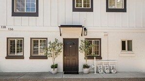 A two-story building with a dark brown front door, potted plants, and a bench. - Walkable Downtown Spa Retreat (Bend)