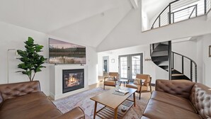 A modern living room with a fireplace, leather sofas, a coffee table, and a staircase. - Walkable Downtown Spa Retreat (Bend)