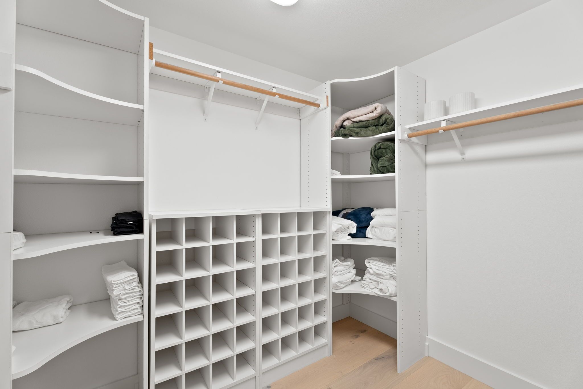 Un dressing avec de nombreuses étagères et un espace de rangement pour suspendre les vêtements, le tout organisé de manière pratique.
