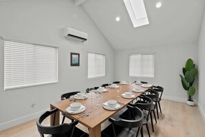 A dining room with a long table set for six, white walls, and a ceiling with skylights. - Walkable Downtown Spa Retreat (Bend)