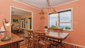 Un comedor con una mesa y sillas de madera, una lámpara colgante y vistas al exterior a través de una ventana.
