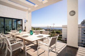 An outdoor patio with a dining table and chairs, a clock on the wall, and a view of the cityscape. - Lavish Villa With Private Pool (Marbella)