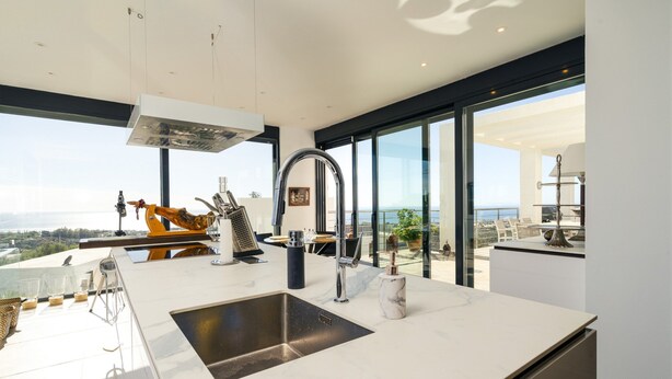 A modern kitchen with a large island, a stainless steel sink, and a view of the sea. - Lavish Villa With Private Pool (Marbella)