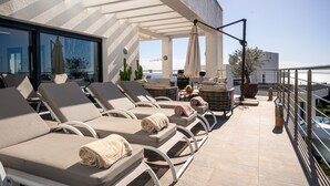 A rooftop terrace with sun loungers, a table with chairs, and a view of the sea. - Lavish Villa With Private Pool (Marbella)