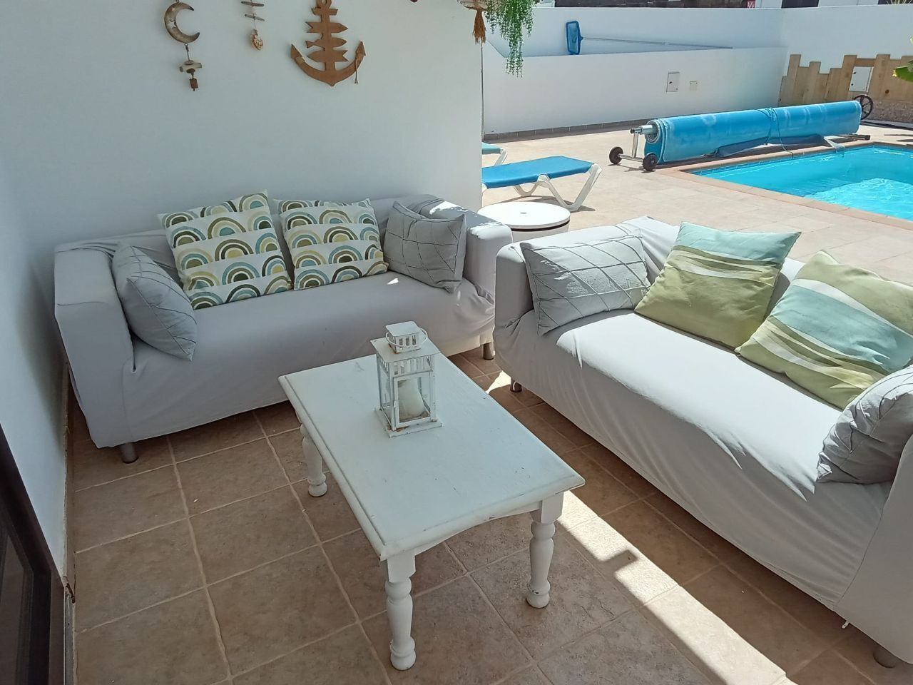 A living area with a sofa, a coffee table, and a pool in the background.