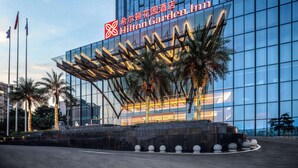 Un moderno Hilton Garden Inn con fachada de vidrio y una estructura de marquesina distintiva.