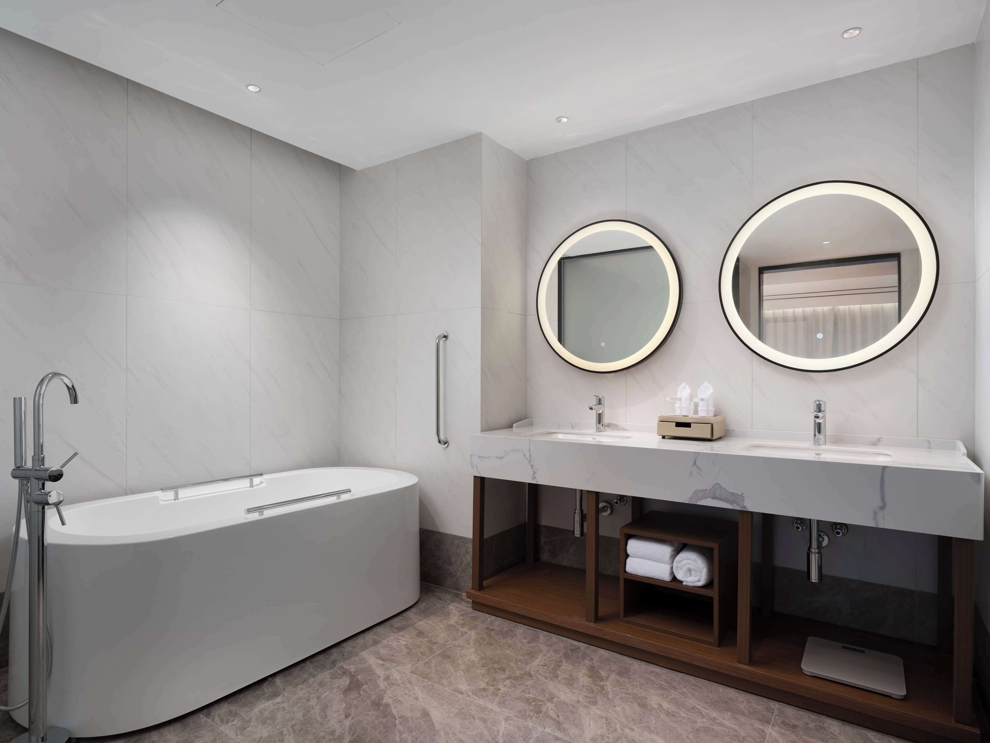 A modern bathroom with a freestanding bathtub, a vanity with a mirror, and a towel rack.