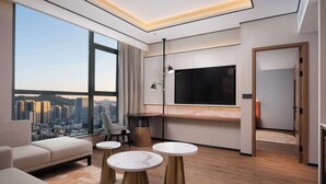 Una sala de estar moderna con un televisor grande, asientos cómodos y vistas a la ciudad.
