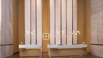 Reception area with sleek desk and two sinks, each paired with a vase and a single flower.