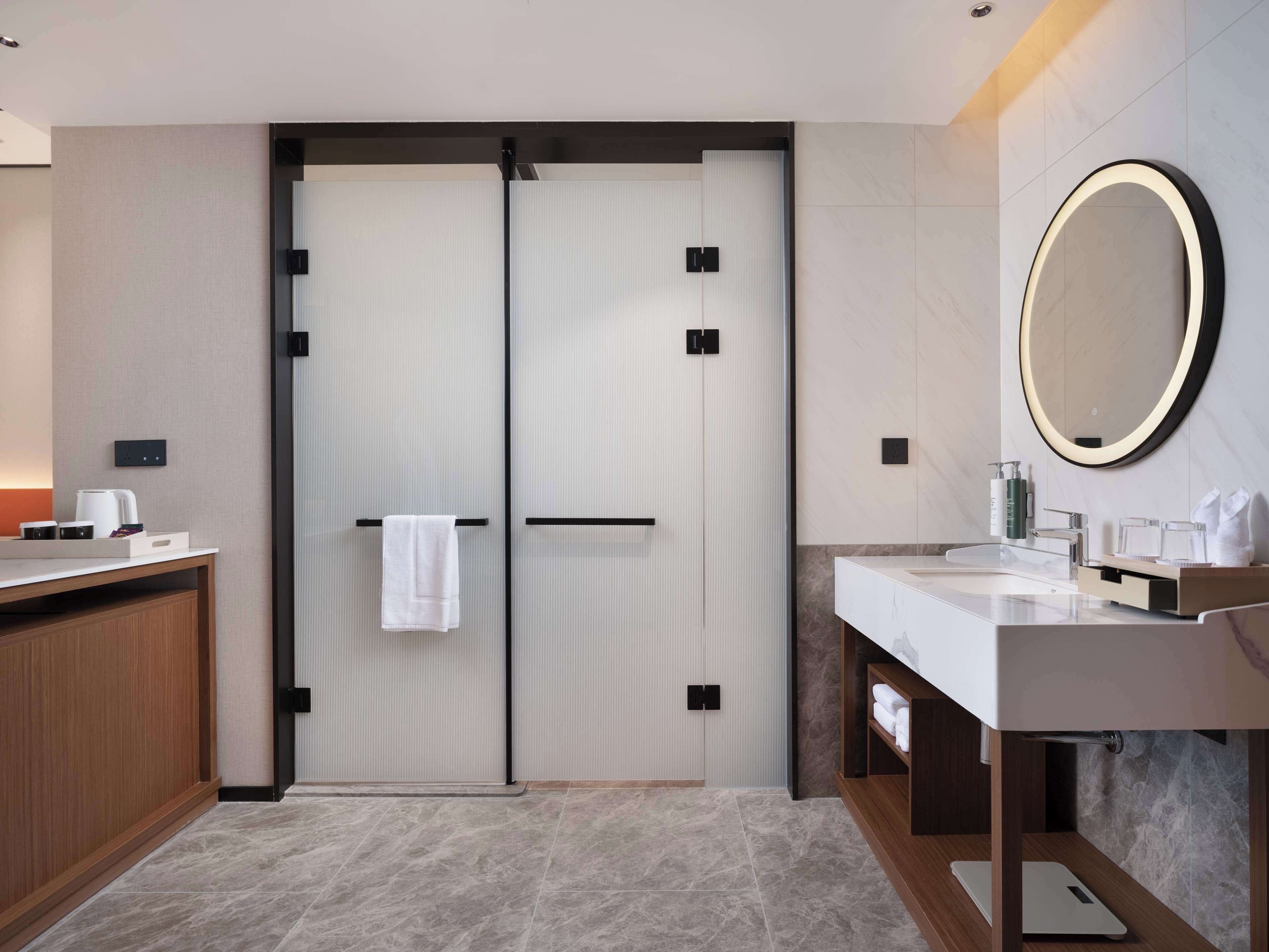 A modern bathroom with a double door, a vanity with a mirror, and a countertop with toiletries.