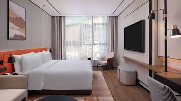 Una habitación de hotel moderna con una cama grande, un escritorio, una silla, un televisor y una ventana con cortinas.