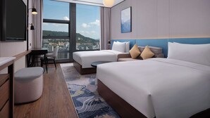 Una habitación de hotel moderna con dos camas, un escritorio y vistas a un paisaje urbano.