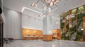 A modern hotel lobby with a reception desk, seating area, and decorative ceiling lights. - Hilton Garden Inn Danzhou Yangpu (Danzhou)