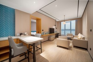 A modern living room with a sofa, chairs, a dining area, and a view of the sea. - Hilton Garden Inn Danzhou Yangpu (Danzhou)