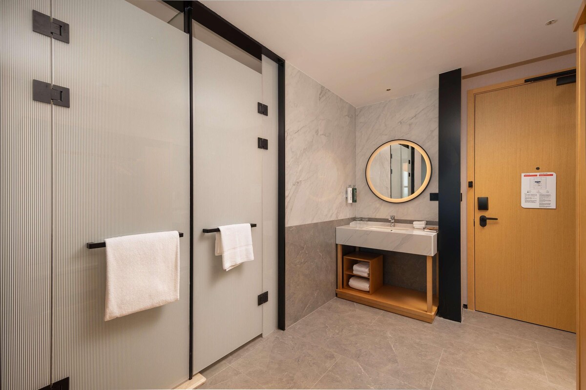 Un baño moderno con puerta corredera, un lavamanos con espejo y una puerta de madera.