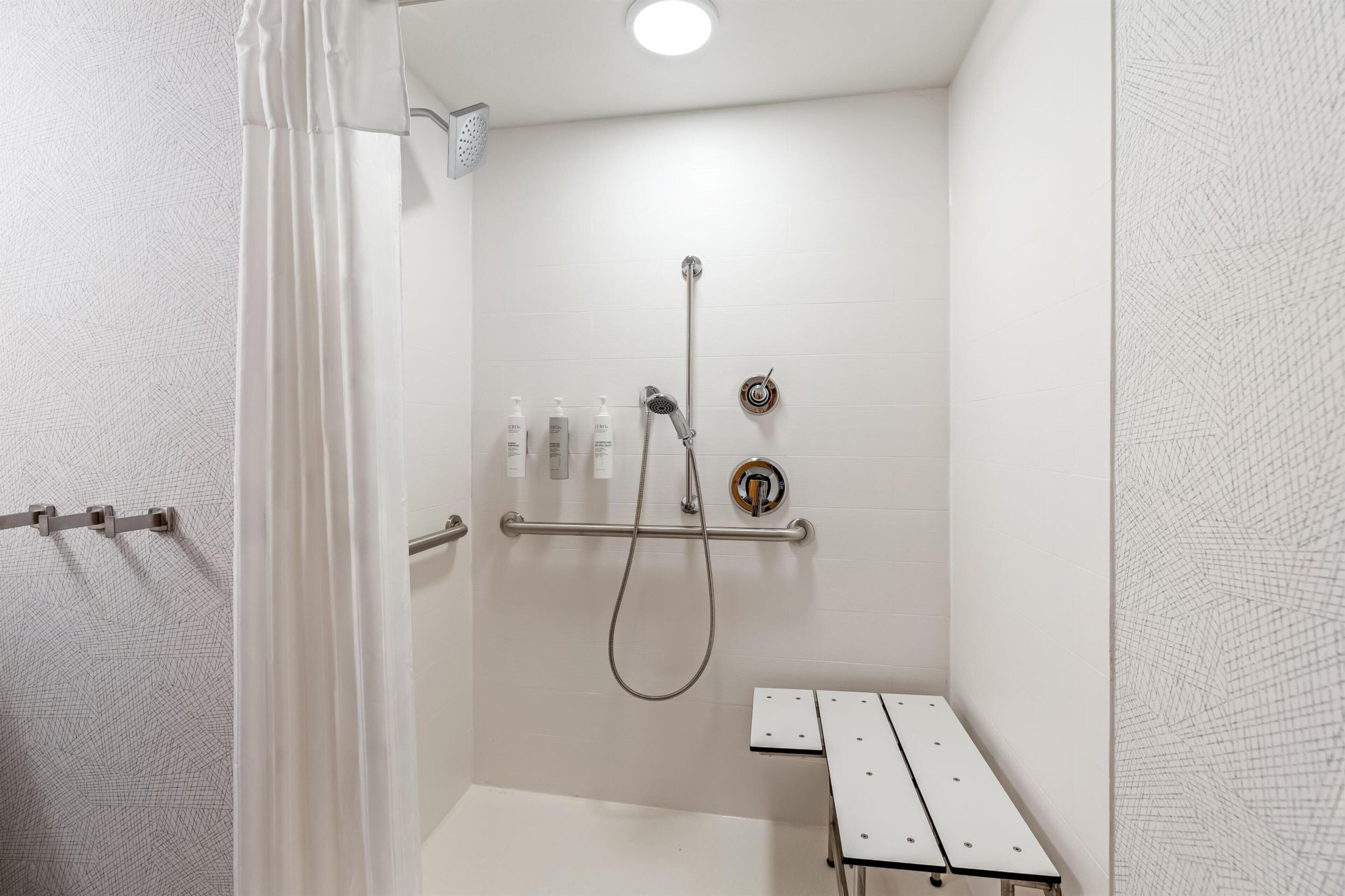 Douche met een handdouche, een wandmengkraan en een glazen douchewand.