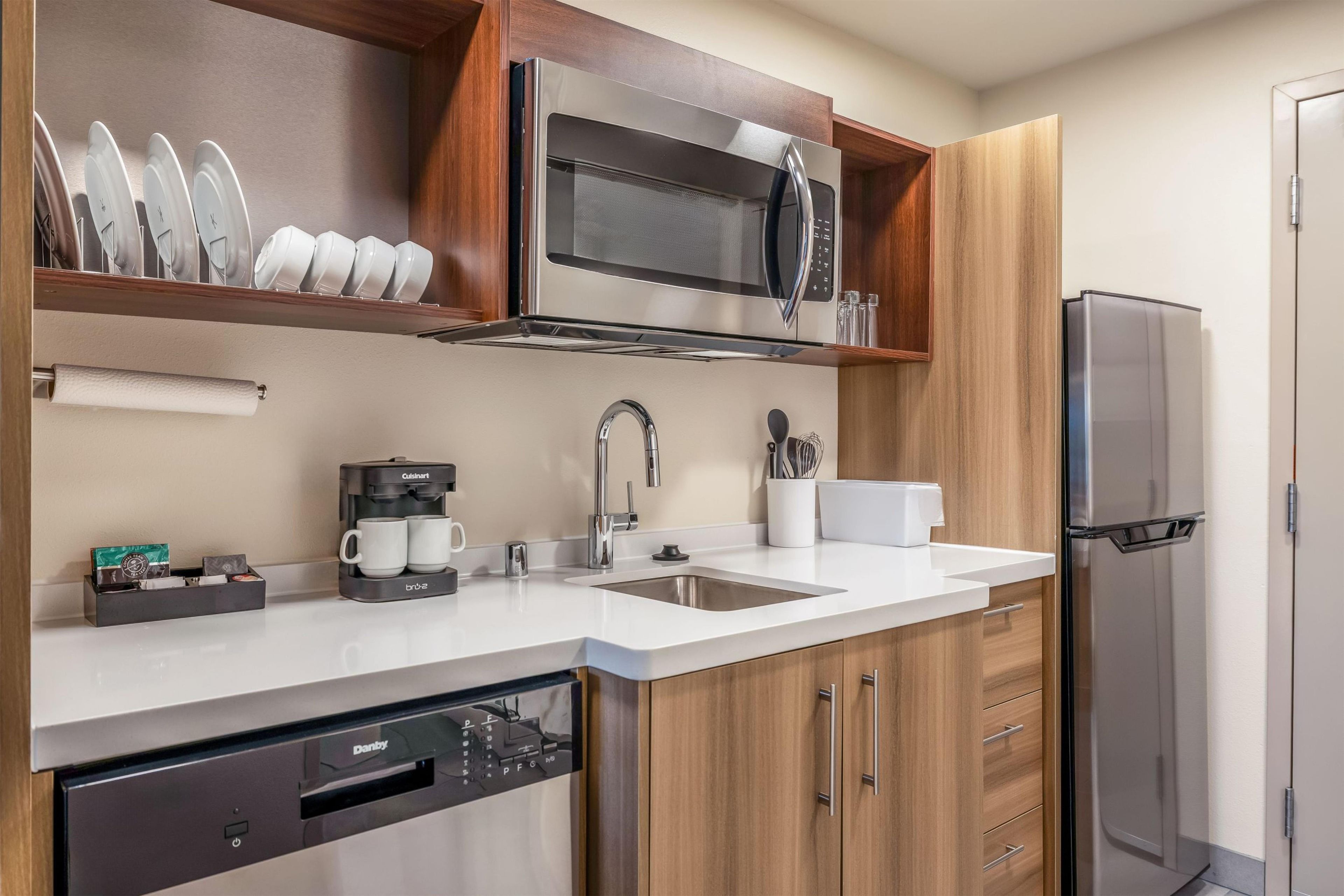 A modern kitchen with a built-in microwave, coffee maker, and dishwasher.