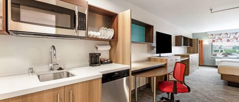 Una cocina moderna con microondas integrado, lavamanos de acero inoxidable y cafetera.