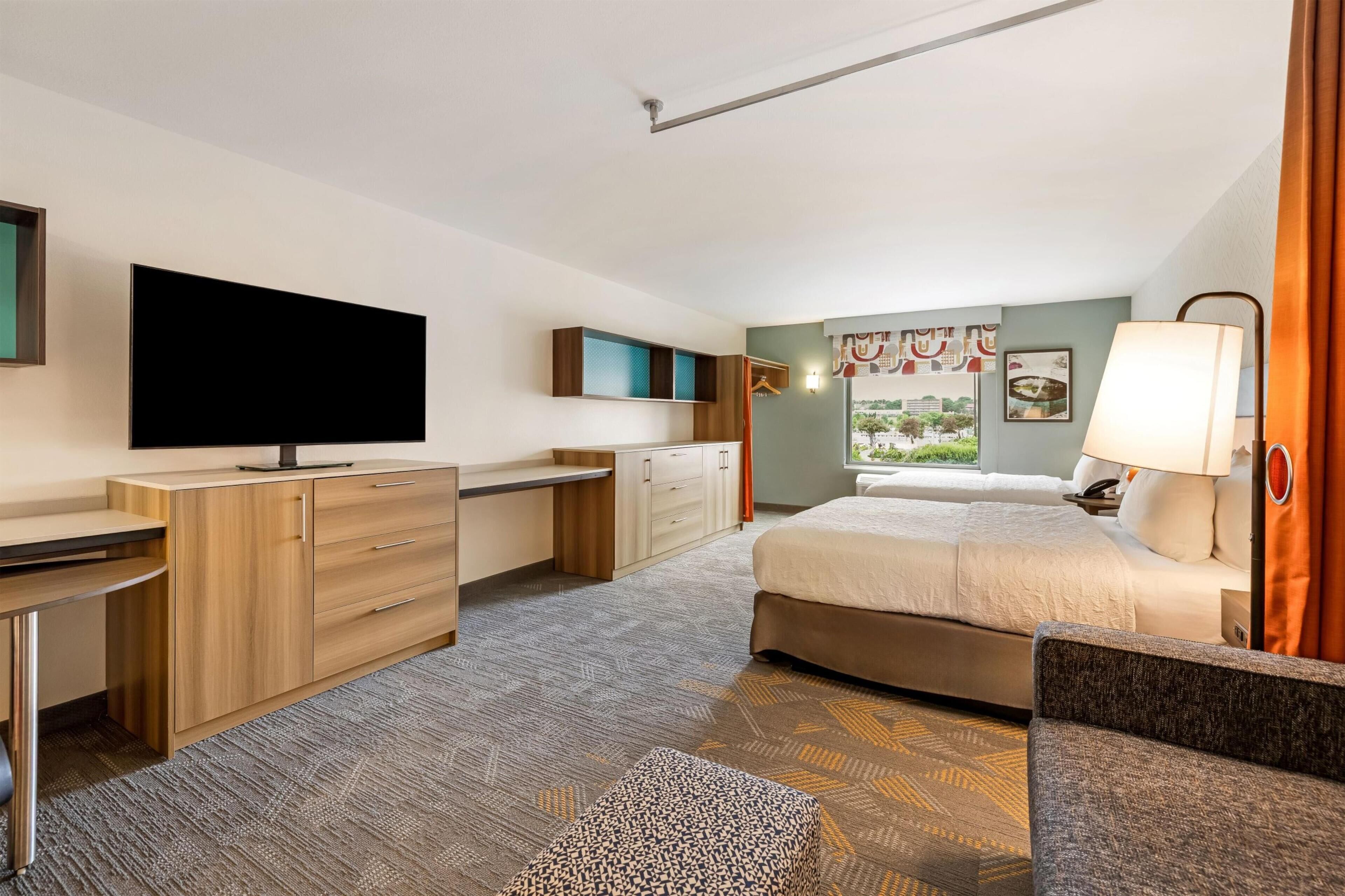 Ein Hotelzimmer mit Bett, Schreibtisch, Fernseher, Kleiderschrank und einem Fenster mit Blick.