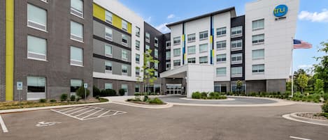 A modern hotel with multiple floors, a parking lot, and an American flag.