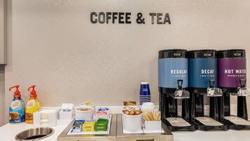 A coffee and tea station with dispensers labeled 'Regular,' 'Decaf,' and 'Hot Water,' along with various tea bags and condiments.