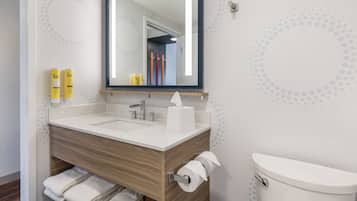 A modern bathroom with a wooden vanity, two sinks, a mirror, and a toilet.