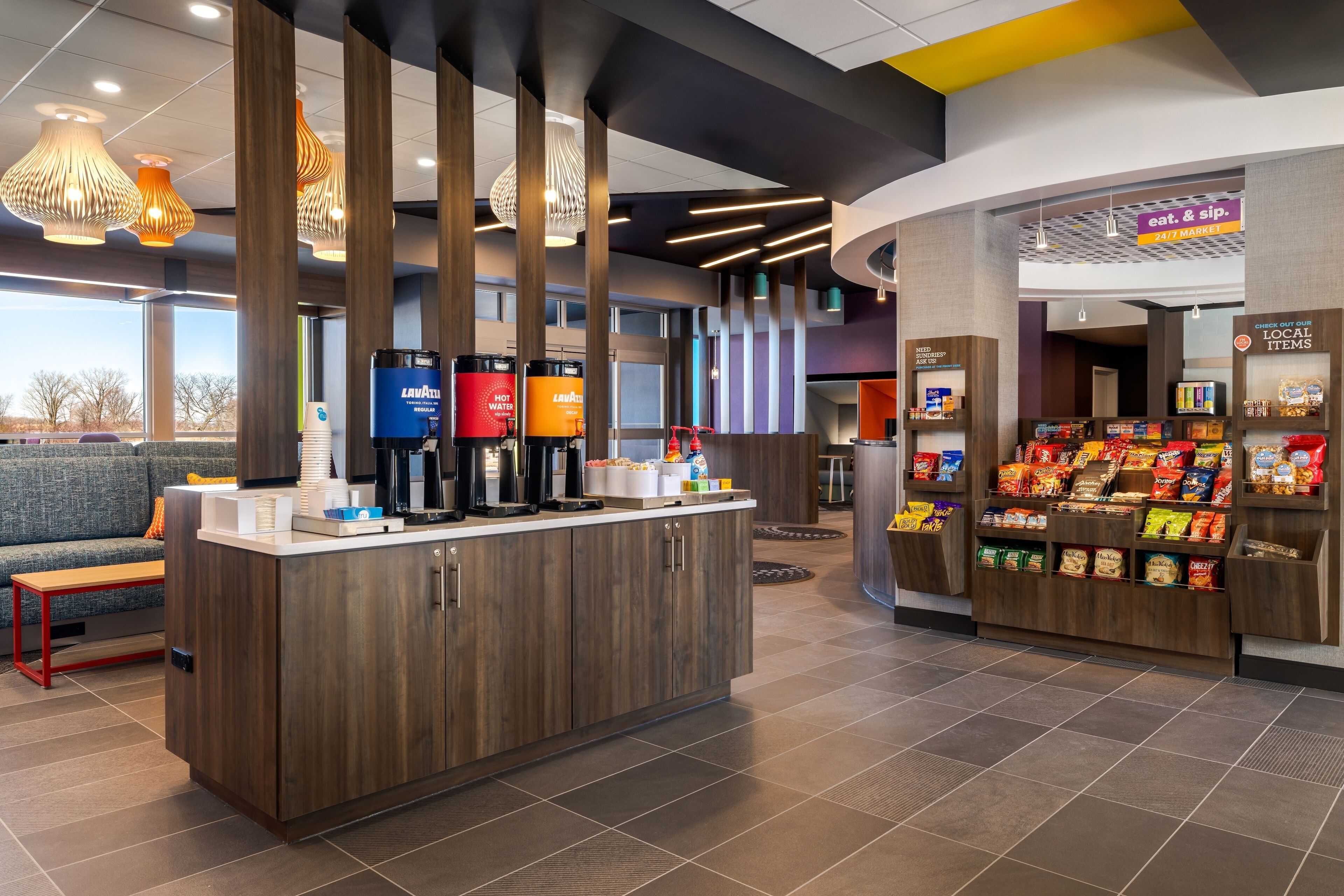 A modern coffee station with a counter, beverage dispensers, and a snack display.