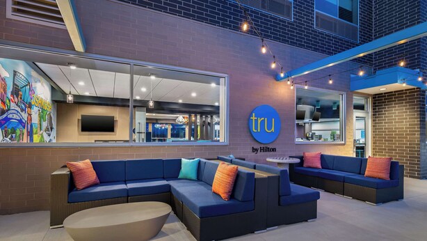 Eine moderne Hotelhalle mit einer großen blauen Couch, einem runden Tisch und einem Wandgemälde.